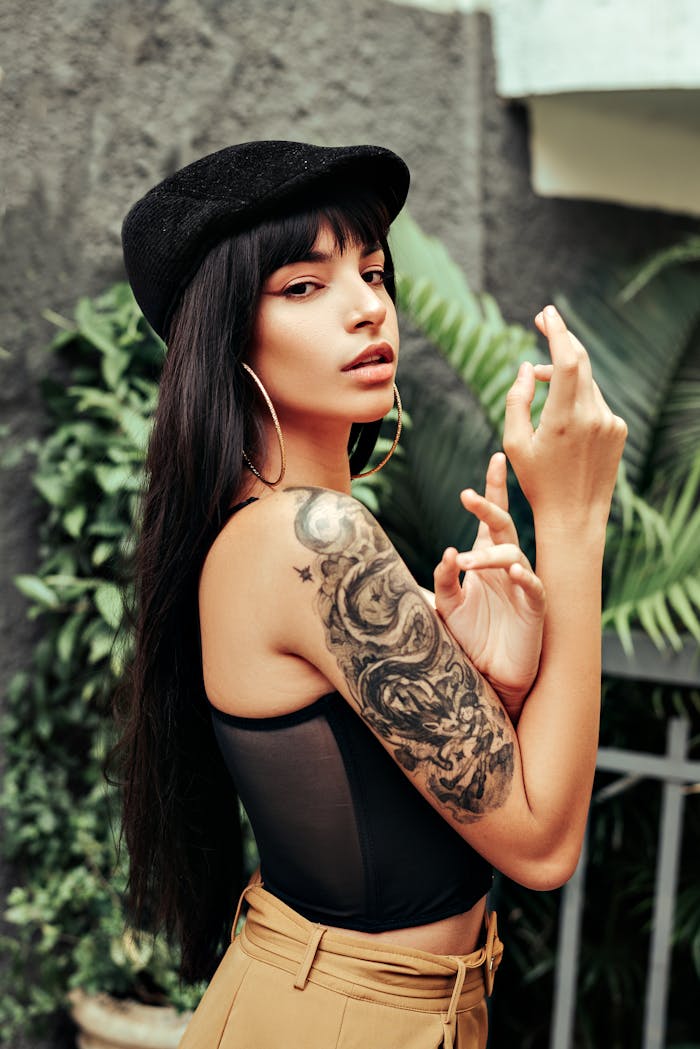 Elegant woman with long hair and tattoo posing outdoors in beret.